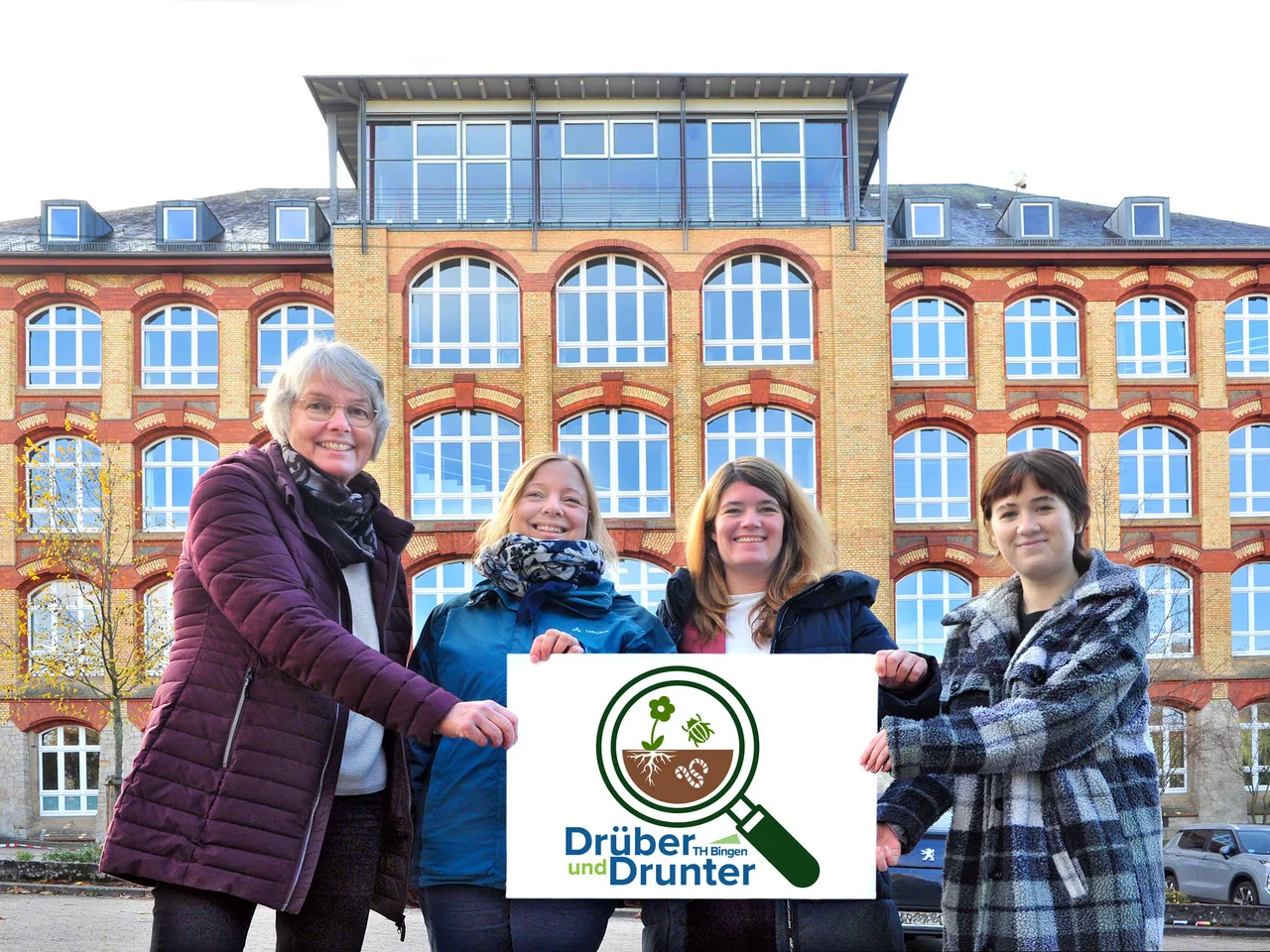 Projektbetreuer vor dem Stadtgebäude und Projektlogo