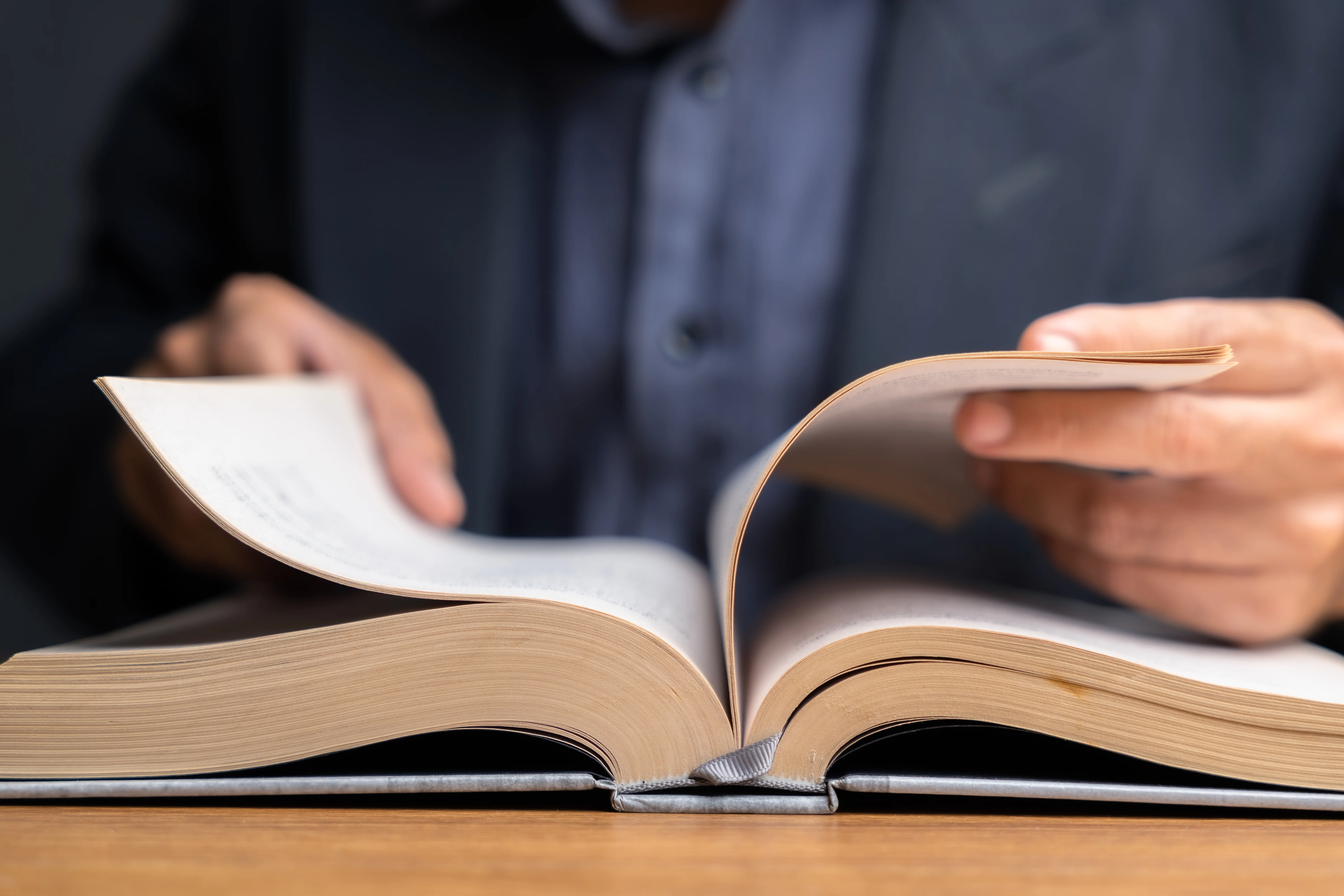 Ein Mann schlägt etwas in einem Buch nach.