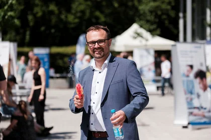 Mann spritzt Wasser aus Wasserpistole in Richtung Betrachter