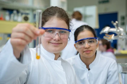 Zwei Schülerinnen im Labor der TH Bingen. Eine davon hält ein Reagenzglas in den Vordergrund.