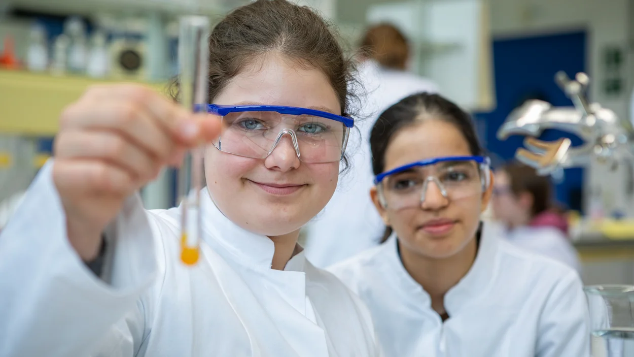 Zwei Schülerinnen im Labor der TH Bingen. Eine davon hält ein Reagenzglas in den Vordergrund.