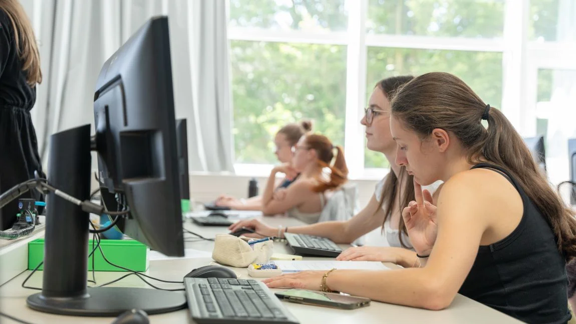 Zwei Schülerinnen grübeln, wie sie die Aufgabe am Computer lösen können.