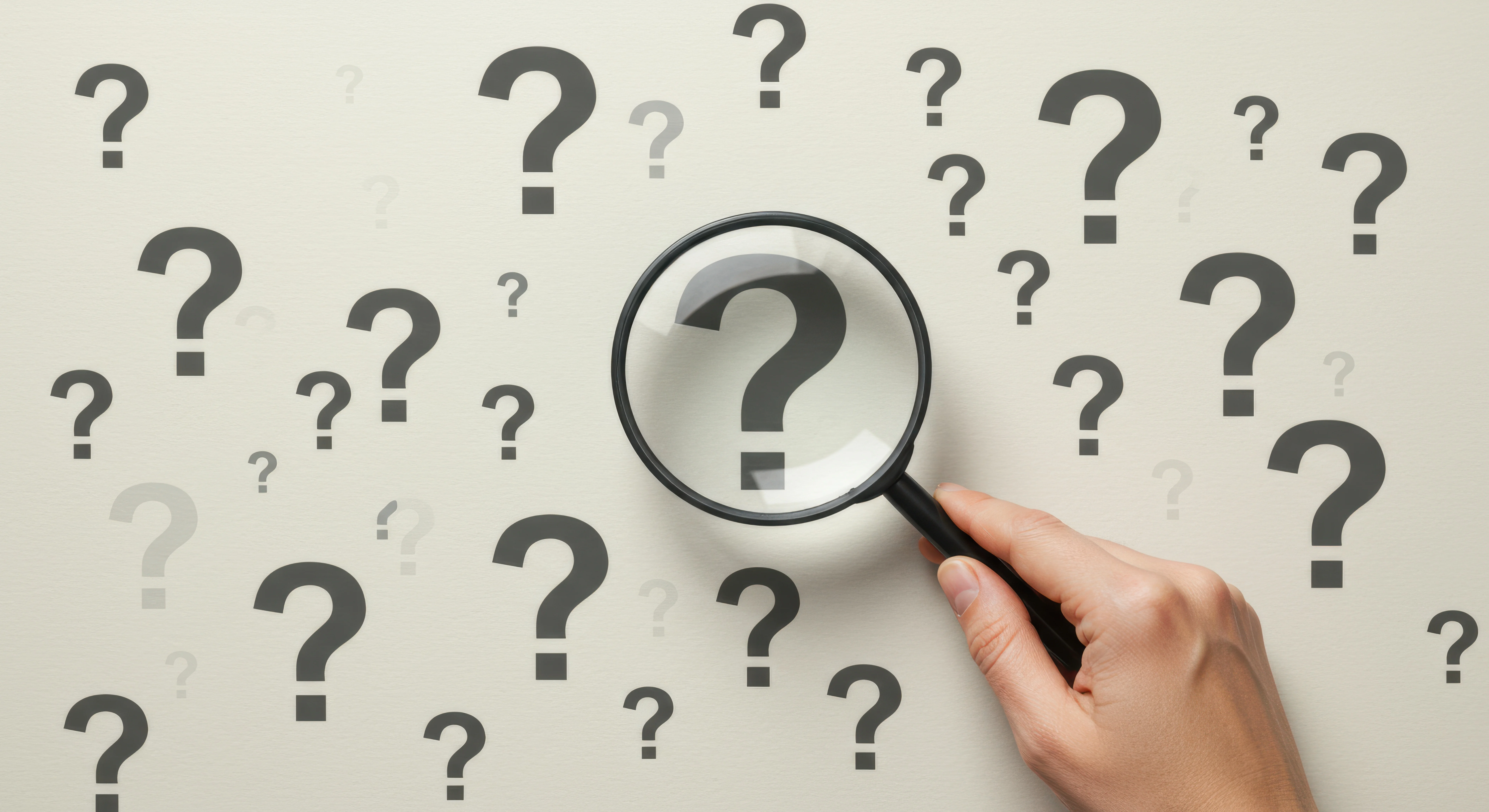 Eine weiße Wand voller Fragezeichen.