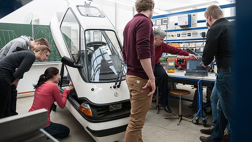 Professor Wrede zusammen mit Studierenden während der Durchfühung von Messungen an einem Elektroauto im Antriebstechniklabor