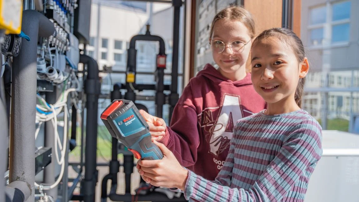 Zwei Mädchen mit Messgerät an einer Anlage