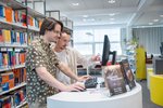 Zwei junger Männer stehen vor einem Bildschirm an einem Stehtisch in der Bibliothek