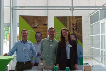 Drei fröhliche Helfer:innen an ihrem Stand der Umweltmesse