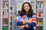 Dunkelhaarige Studentin mit Brille und Büchern