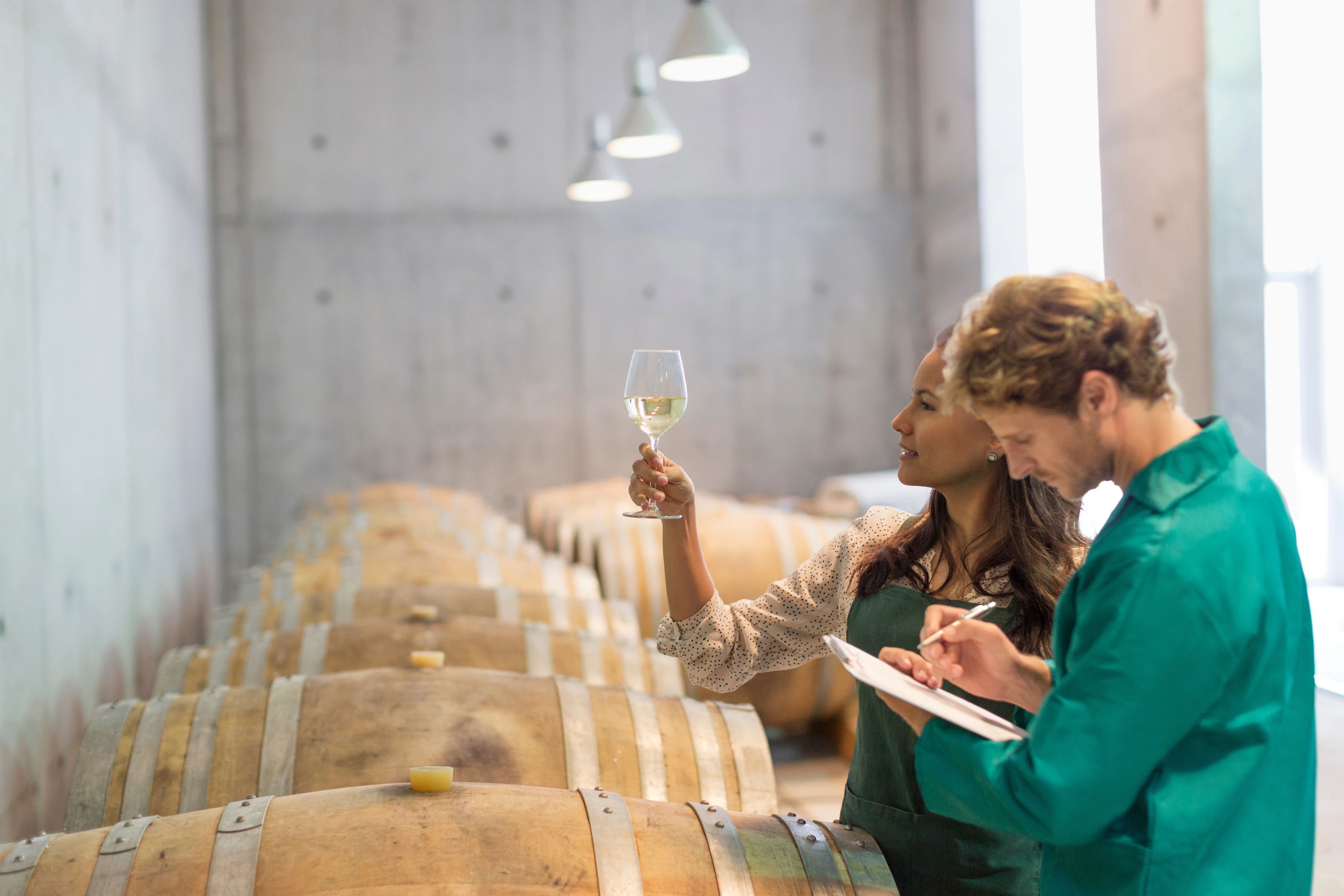 Winzer und Winzerin prüfen Weißwein im Weinkeller