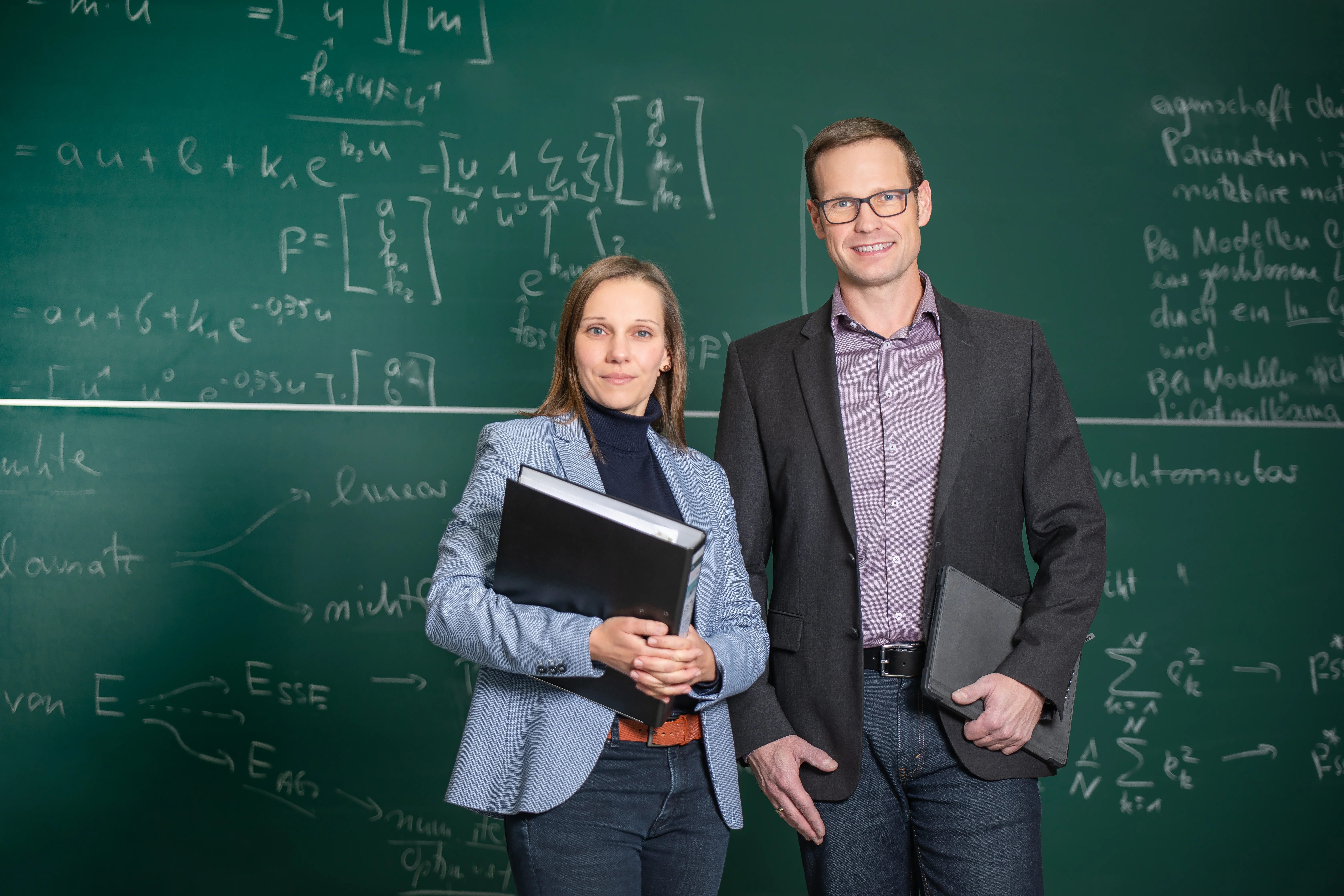 Zwei Profs vor einer Lehrtafel mit mathematischen Zeichen