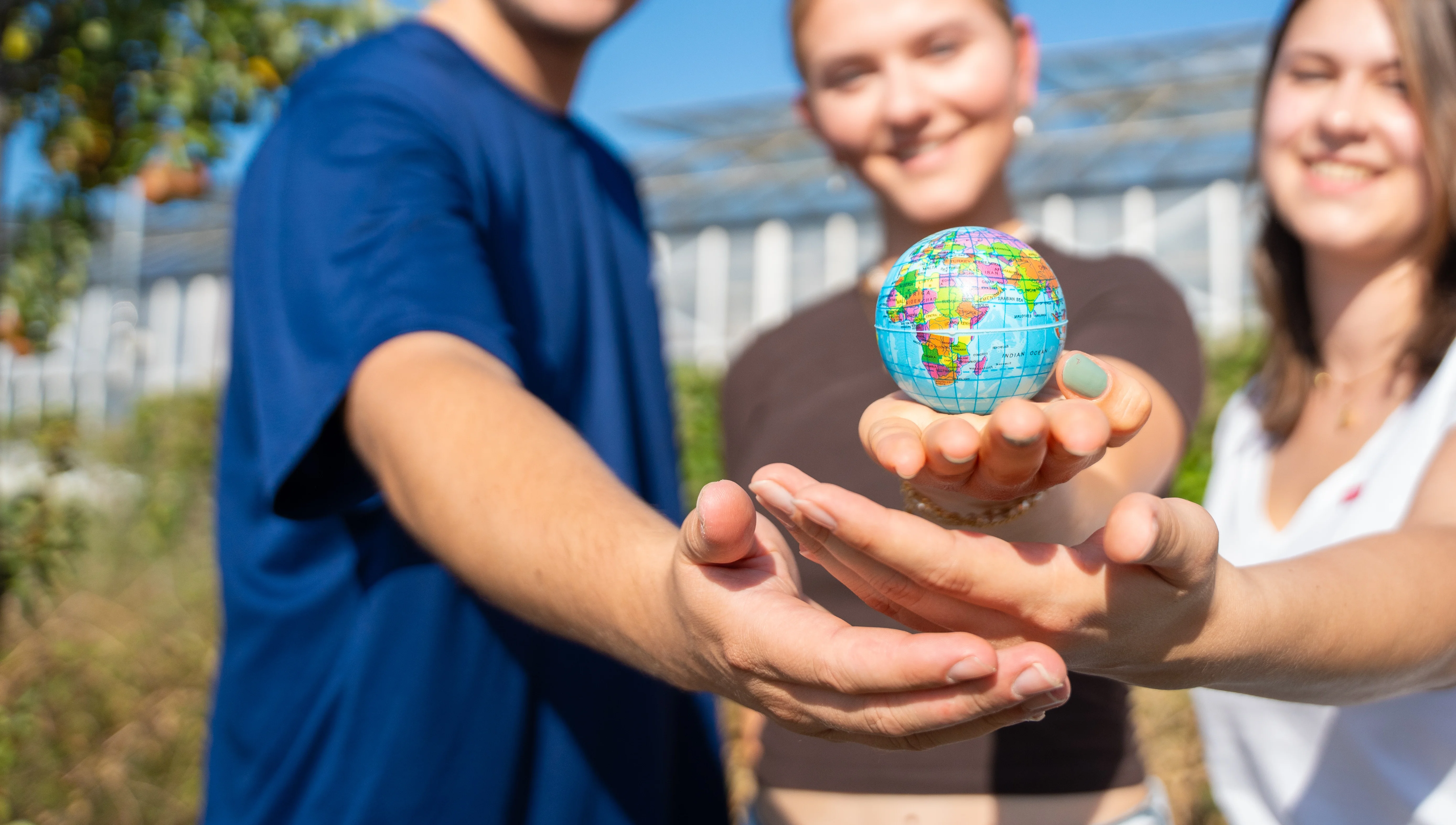 drei StudentInnen halten die Erde