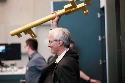 Mann hält einen großen goldenen Schlüssel in die Höhe