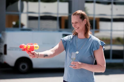 Frau hält große Wasserpistole und Sektglas