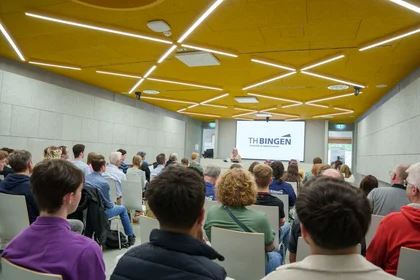 Menschen sitzen im neuen Seminarraum und lauschen einer Rede