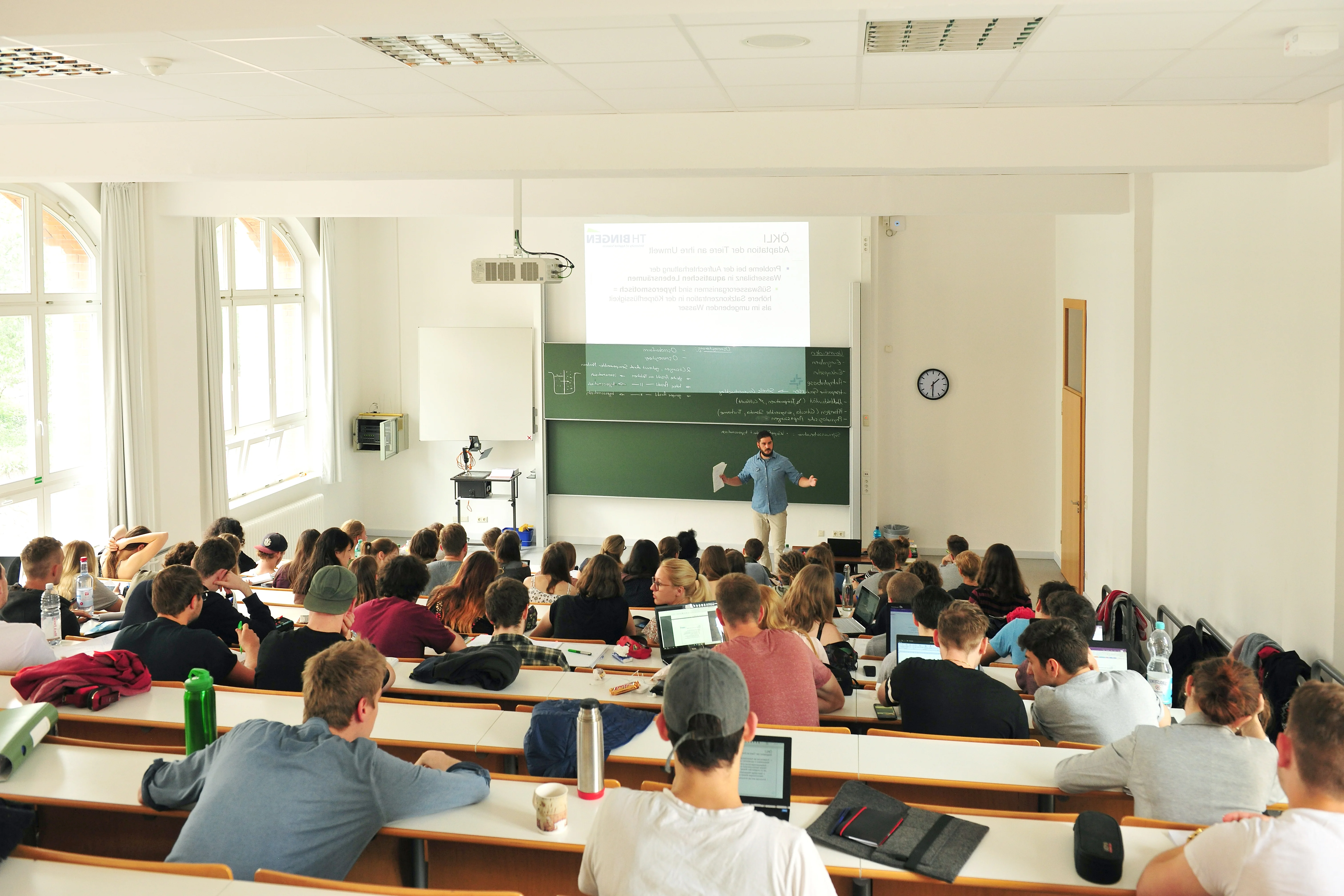 Vorlesungssituation an der TH Bingen: Vorne ein Professor vor seinen Folien, hinten die Studierenden im Hörsaal.