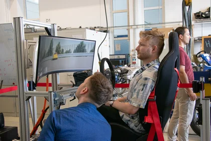 Zwei Besucher sehen sich den Fahrsimulator an