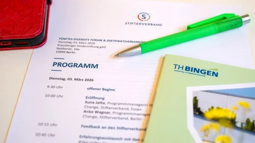 Programm der Veranstaltung, grüner Stift und grünes Buch mit TH-Bingen-Logo