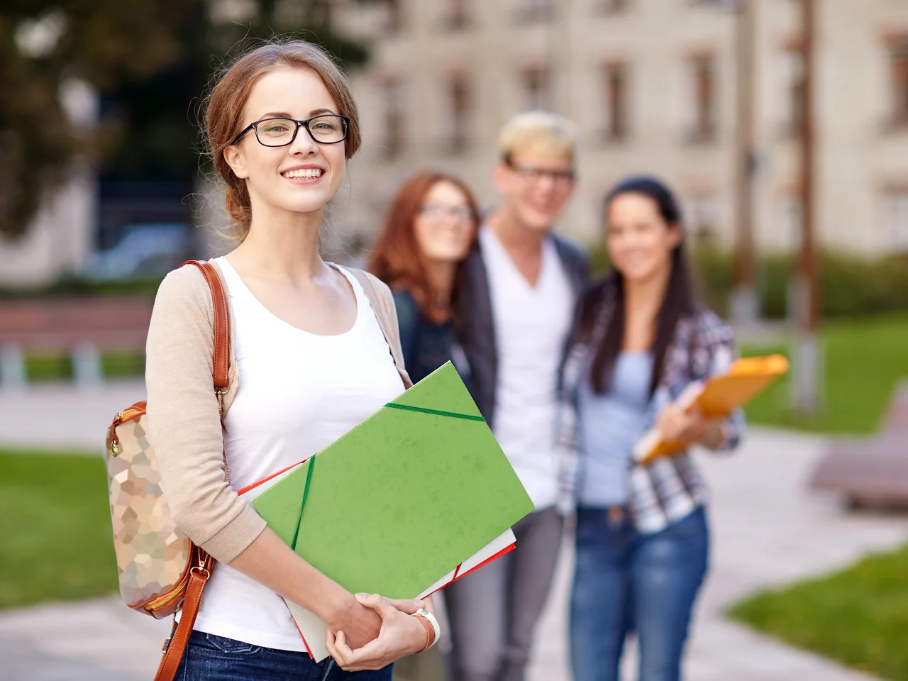 Studierende auf einem Campus mit Lehrmaterial in den Händen.