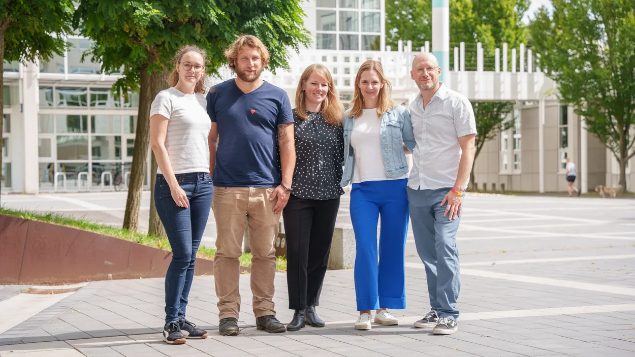 Fünf Personen stehen nebeneinander vor Bäumen auf dem Campus der TH Bingen