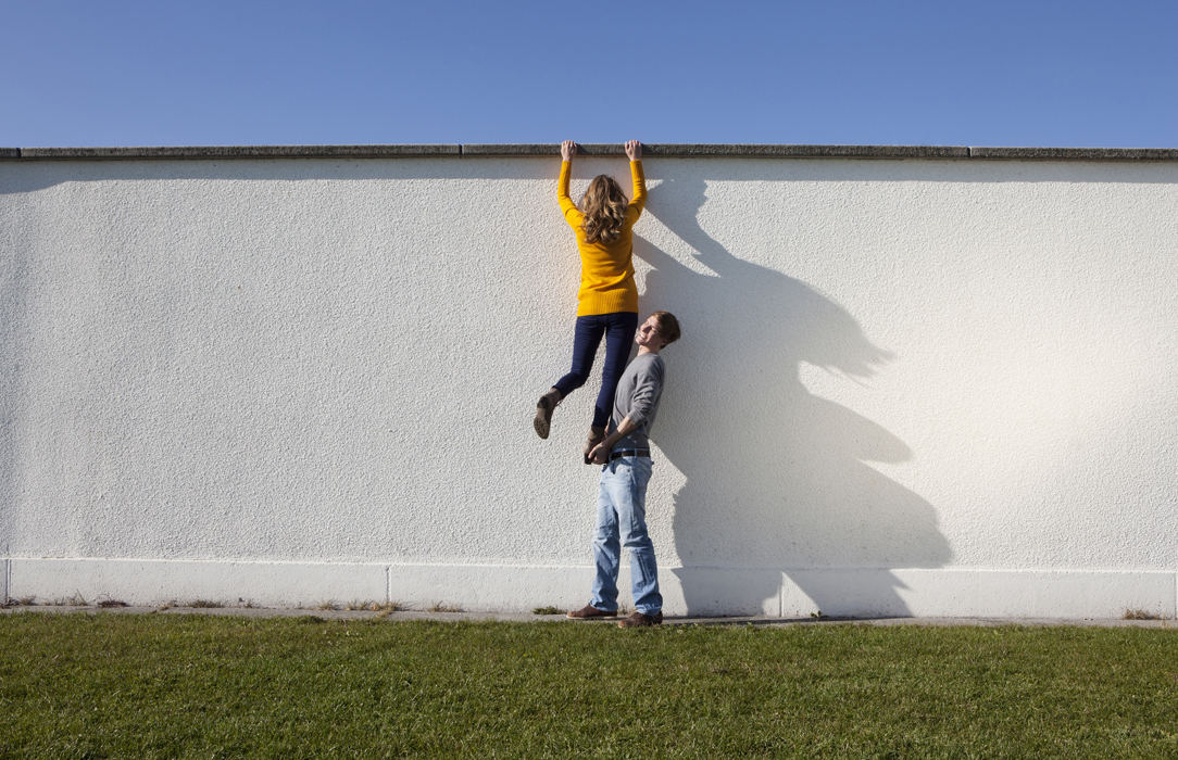 Mann hilft Frau beim Übersteigen einer Mauer